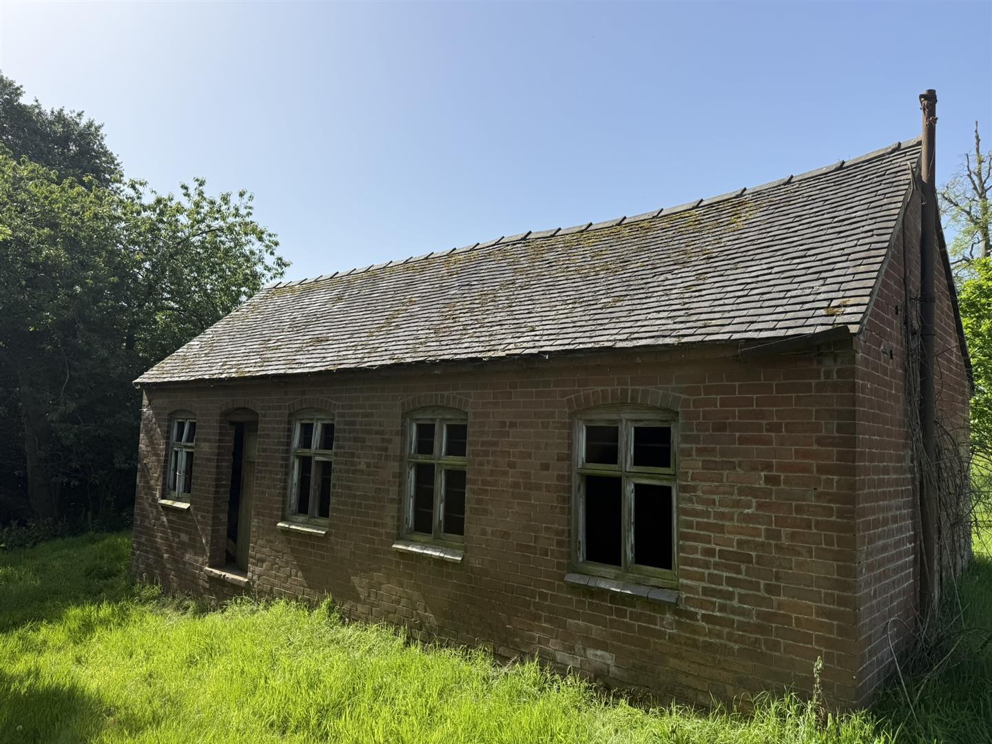 The Pump House before restoration, a low brick building with a pitched slate roof.